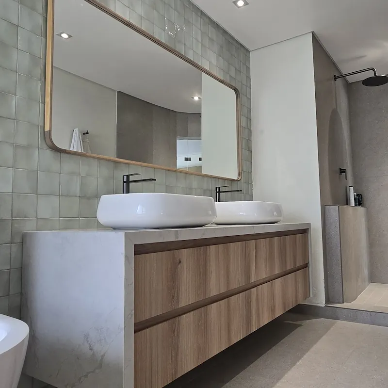 A natural and earthy luxury bathroom vanity with white stone counters and timber draw detail