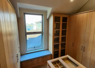 A classic and elegant walk in closet with natural timber elements complimented by glass detail cabinets and mirror backings.