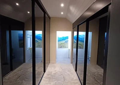 A sleek, modern yet minimal walk in closet with grey tinted mirror sliding doors and cool white led lighting