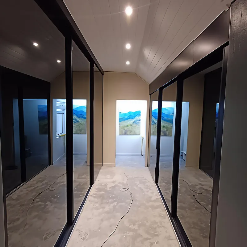 A sleek, modern yet minimal walk in closet with grey tinted mirror sliding doors and cool white led lighting