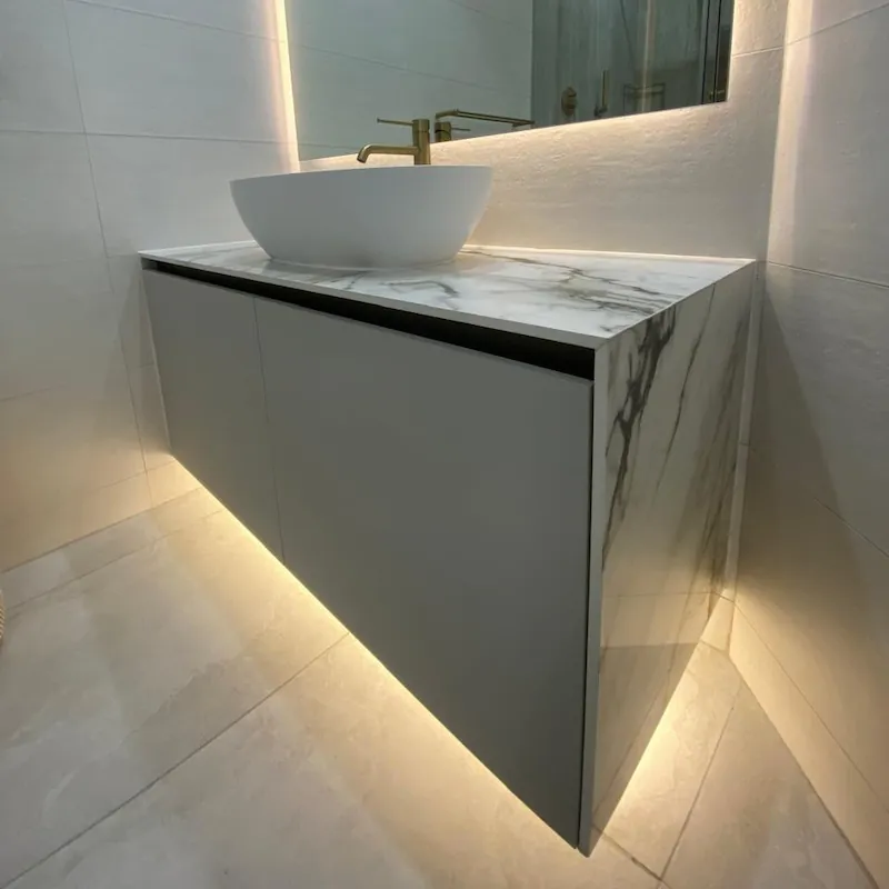 A minimalist floating bathroom vanity with matte grey doors and luxurious waterfall stone top