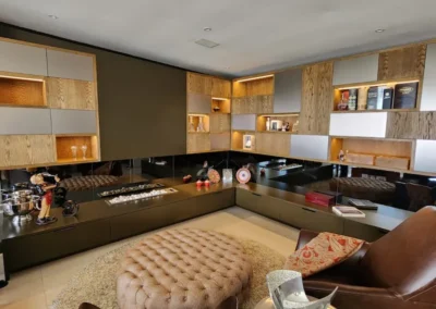 A statement piece TV unit with white oak veneer details, brushed brass cabinet doors compliments by grey tinted mirrors and built in fire place.