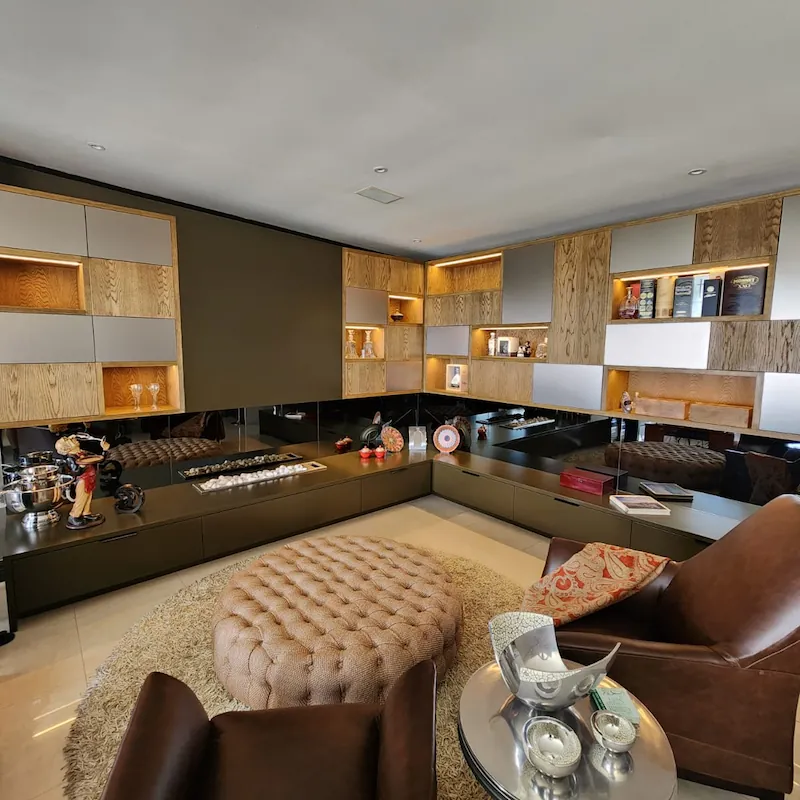 A statement piece TV unit with white oak veneer details, brushed brass cabinet doors compliments by grey tinted mirrors and built in fire place.
