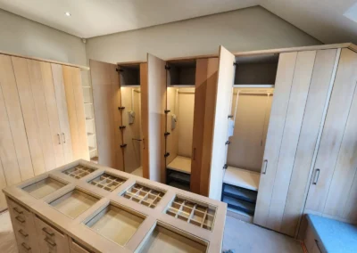 Custom walk-in closet island with drawer storage, glass display tops and full-height timber wardrobe cabinetry