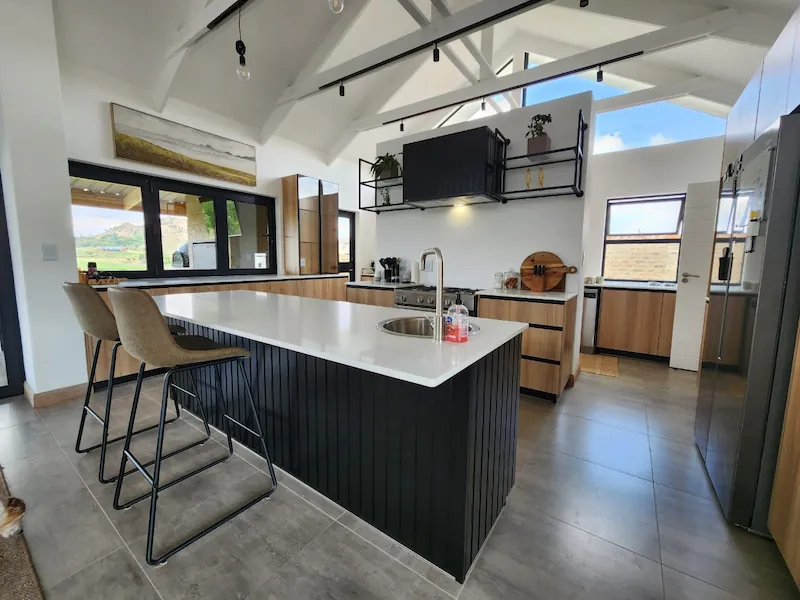 Custom Kitchen Cabinetry Johannesburg Open Plan Island Custom kitchen cabinetry in Johannesburg with black island, timber cupboards, open-plan layout and integrated storage by Oakmont Kitchens & Interiors