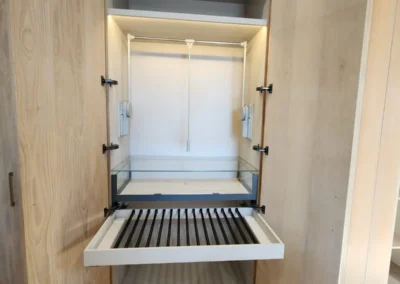 Custom wardrobe interior with pull-down hanging rail, pull-out tray, glass-front storage and integrated LED lighting