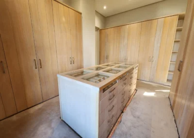 Custom walk-in closet at Waterfall Equestrian Estate with timber cabinetry, central island drawers and glass display storage by Oakmont Kitchens & Interiors
