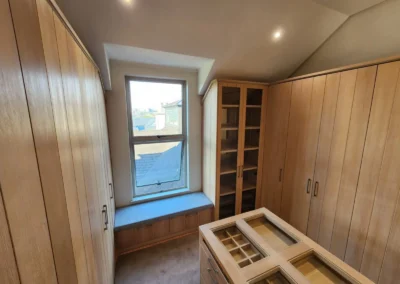 Walk-in closet in Waterfall Equestrian Estate featuring timber cabinetry, central island storage, glass display tops and window seating