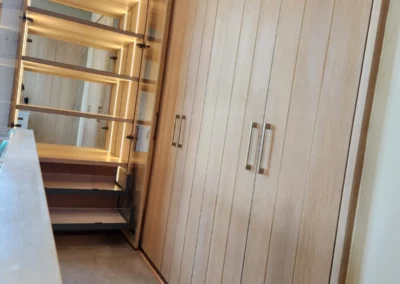 Dressing room cabinetry with timber wardrobes, glass display cabinet, central island storage and full-height closet doors
