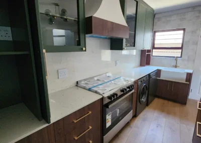 Custom kitchen in Bedfordview with green upper cabinets, timber base cabinetry, stone-look surfaces and integrated appliances