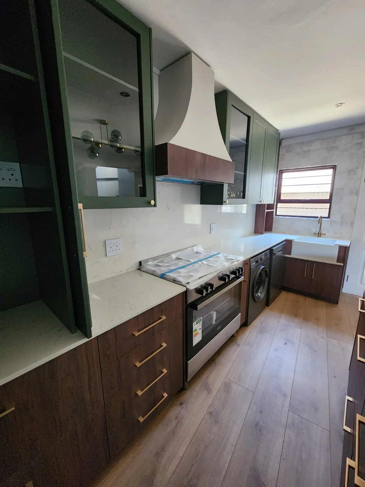 custom-kitchen-bedfordview-green-cabinetry-timber-accents Custom kitchen in Bedfordview with green upper cabinets, timber base cabinetry, stone-look surfaces and integrated appliances