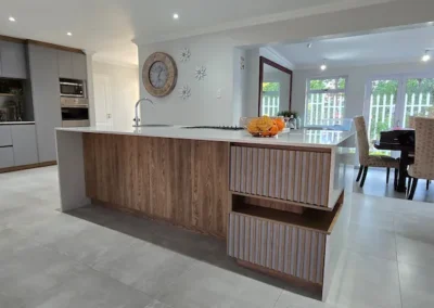 Custom kitchen in Modderfontein with grey cabinetry, timber island detailing, integrated appliances and open-plan dining area by Oakmont Kitchens & Interiors